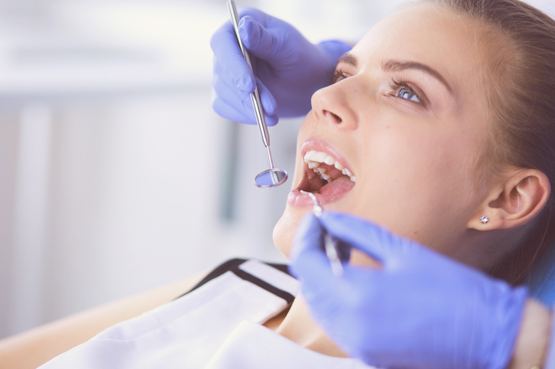 Young Female patient with open mouth examining dental inspection at dentist office