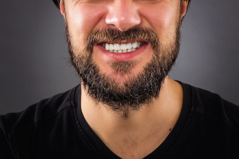 Closeup of  stressed man mouth isolated on gray background